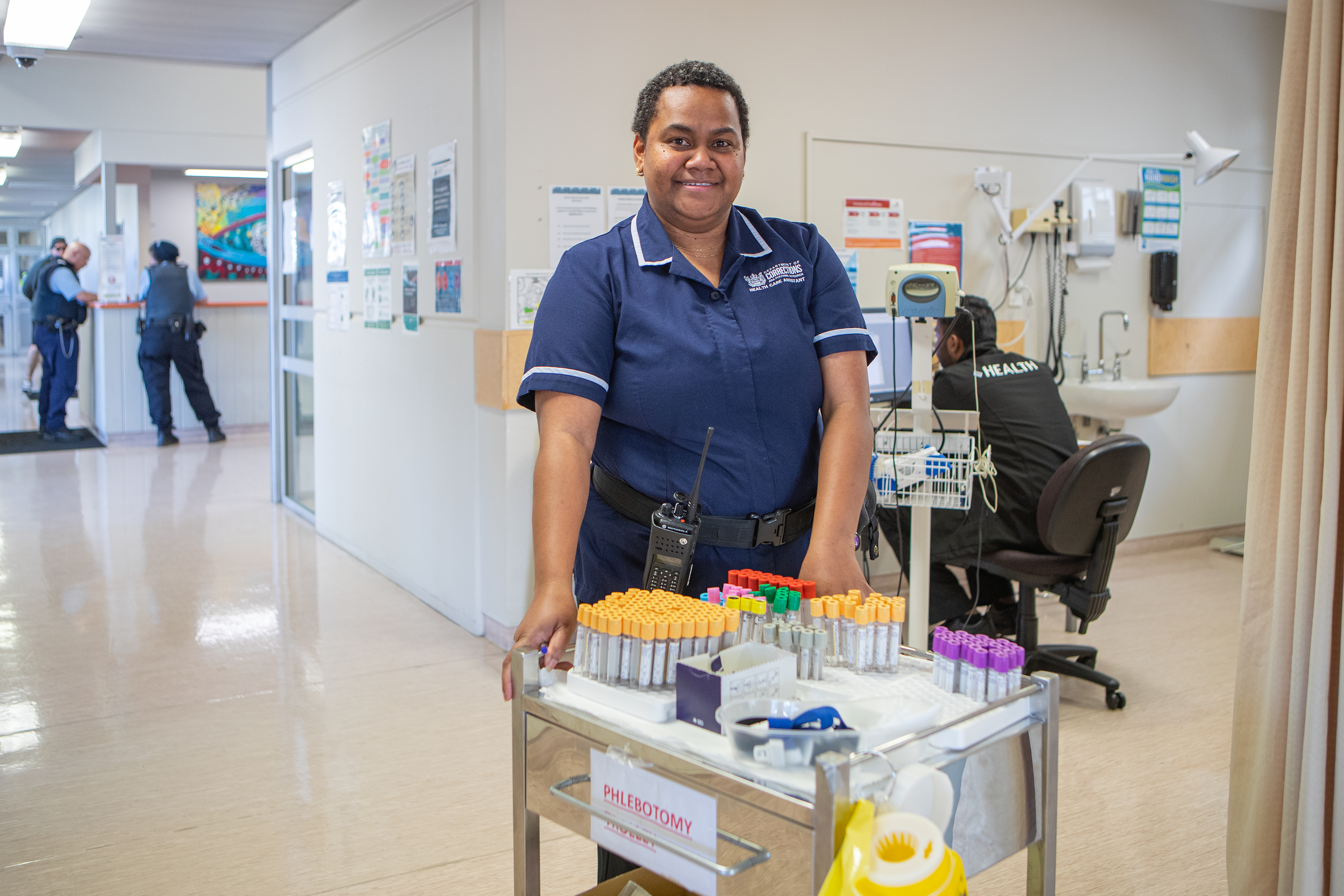 Nurse in the healthcentre stands behind trolley of medical equipment