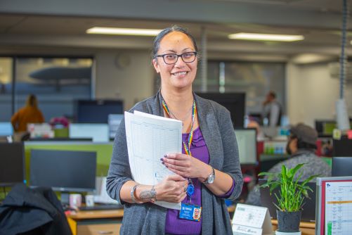 Staff member stands in office with folder
