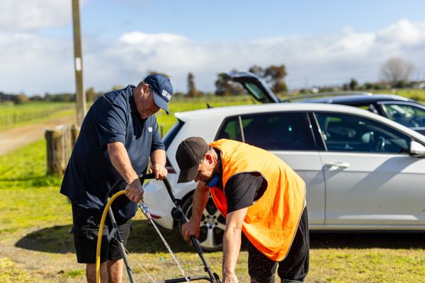 Community Work Supervisor works with a person on community sentence to spray down a piece of equipment